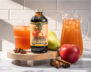 A pitcher of harvest sangria with sliced apple, pear, and cinnamon sticks, made with Portland Syrups Apple Crisp Syrup.