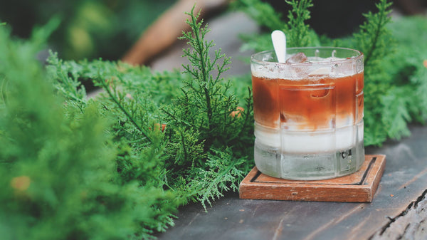 Refreshing iced coffee with cream amidst lush greenery, evoking a peaceful outdoor vibe.